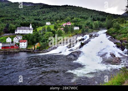 Der Hellesyltfossen Wasserfall im Dorf Hellesylt am Kopf des Sunnylvsfjorden, Norwegen, mit der Sunnylven Kirche auf dem höheren Boden Stockfoto