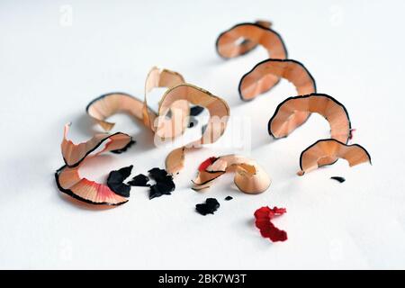 Späne aus einem kosmetischen Bleistift auf weißem Hintergrund. Holzstücke aus einem Bleistiftspitzer für Eyeliner und Lippen. Sägemehl eines Bleistifts. Stockfoto