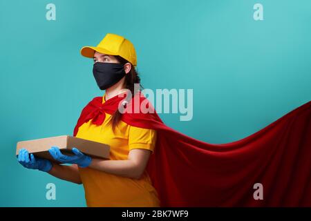 Kurier trägt operative Gesichtsmaske in Superhelden-Mantel. Konzept der Superheldentum Kurier während Coronavirus Ausbruch. Stockfoto