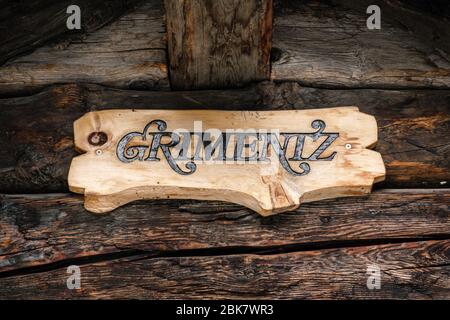 Holzhandwerk-Namensschild von Grimentz, das an alten Holzbrettern in einem Chalet oder Blockhaus hängt. Grimentz, Val d' Anniviers, Wallis, Schweiz Stockfoto