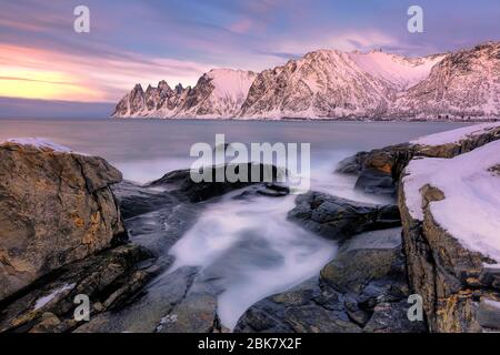 Der felsige Strand und die Pools bei Sonnenuntergang auf Ersfjord. Senja in der Troms-Region Nordnorwegens. Aufnahme mit langer Belichtung Stockfoto