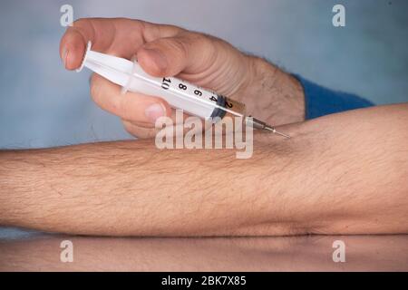 Junge Injektion Medikament mit einer Spritze Nadel in den Arm Stockfoto