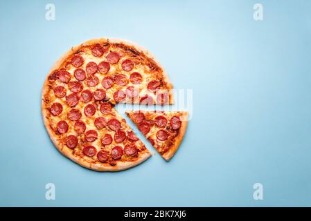 Pepperoni Pizza auf blauem Hintergrund Draufsicht. Traditionelle italienische Küche. Flatlay mit einer hausgemachten Pizza mit heißen Pepperoni und Mozzarella. Stockfoto