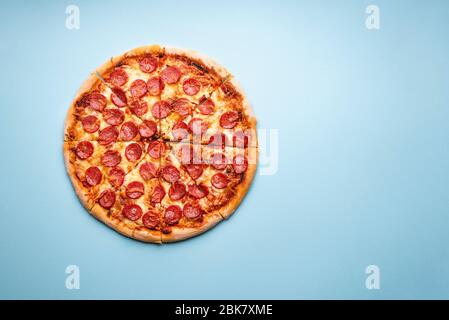 Heiße Pepperoni Pizza auf einem blauen Tisch über der Ansicht geschnitten. Köstliche hausgemachte italienische Küche. Pizza mit heißen Pepperoni und Mozzarella Stockfoto