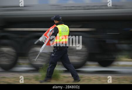 30. April 2020, Hessen, Frankfurt/Main: Ein Zollbeamter richtet ein Warndreieck "Zollkontrolle" ein. Das Hauptzollamt in Frankfurt führt derzeit am Flughafen Lkw-Kontrollen durch. Foto: Andreas Arnold/dpa Stockfoto