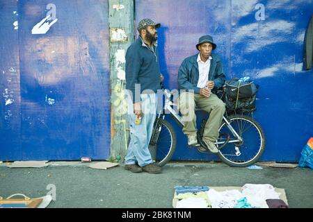 London, Großbritannien - 20. August 2019, zwei ältere Männer verkaufen ihre Sachen auf Asphalt in Bricklane auf einem Flohmarkt am Sonntag Straße. Stockfoto