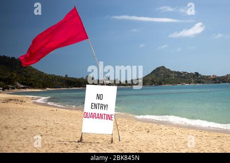 Quarantänekonzept, geschlossene Grenzen, Urlaubsabsage. Tropischer Strand an einem sonnigen Tag ohne Menschen. Es gibt eine rote Flagge und ein Schild mit der Aufschrift no entr Stockfoto