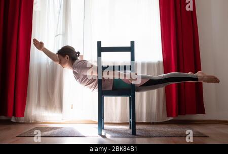 Junge Frau praktiziert Yoga in Superman Pose oder Viparita Shalabhasana Mit Stuhl Stockfoto