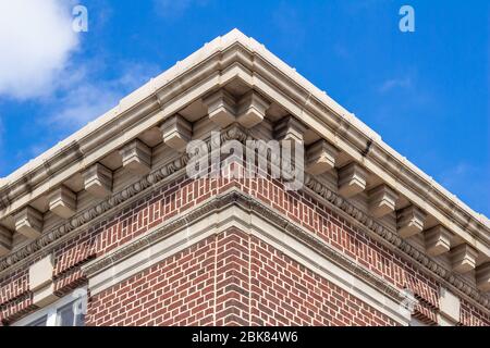 Blick nach oben auf eine verzierte Dachgaue auf einem traditionellen Backsteingebäude mit blauem Himmel Hintergrund Stockfoto