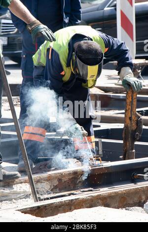 Belgrad, Serbien - 23. April 2020: Schweißer Bauarbeiter arbeiten an der Straßenbahnkreuzung der Stadt, reparieren und ersetzen alte verrottete Schienen Stockfoto