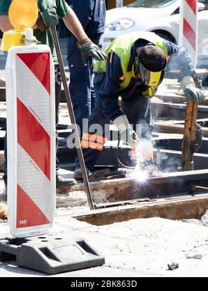 Belgrad, Serbien - 23. April 2020: Schweißer Bauarbeiter arbeiten an der Straßenbahnkreuzung der Stadt, reparieren und ersetzen alte verrottete Schienen Stockfoto