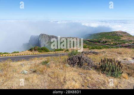 Blick auf die Straße in den Bergen zwischen den malerischen Hängen und über den Wolken. Stockfoto