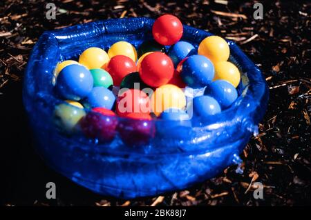 Bunte Kunststoff Kinderkugeln in einem blauen transparenten Planschbecken in einem Garten, Großbritannien Stockfoto