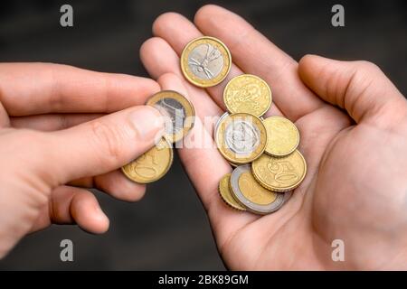 Münzen in der Hand. Hände mit ein paar Euro-Münzen. Eine Hand mit Münzen in der Handfläche. Wirtschaftskrise. Münzen in der Handfläche. Geld in der Hand. Geld, Bargeld zählen Stockfoto