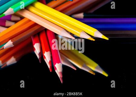 Viele verschiedene Buntstifte auf schwarzem Hintergrund reflektiert Stockfoto