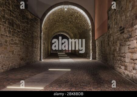 Ein alter, illuminierter historischer Tunnel in der Altstadt und alte Steine an den Wänden Stockfoto