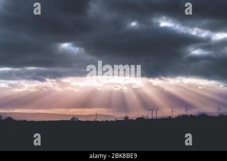 Eine dunkle Wolkendecke am Himmel und Sonnenstrahlen strömen über die Landschaft Stockfoto