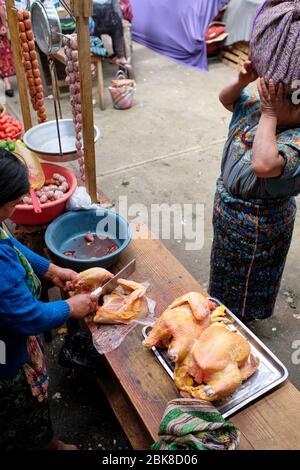 Frau mit traditionellen bunten Kleidern gekleidet Kauf Huhn in einem lokalen Markt Stockfoto