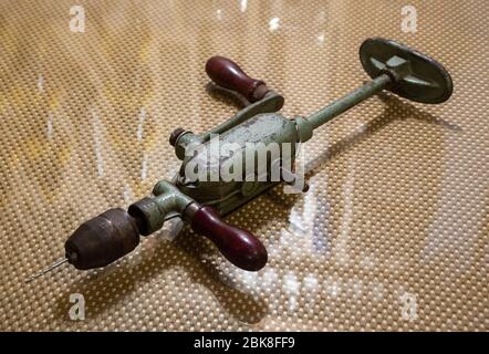 Sehr alte, gebrauchte, antike Handbohrmaschine für Holzbearbeitung auf dem Glastisch, Vintage-Objekt, isoliert Stockfoto