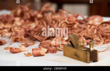 Ein kleiner Messing-Handhobel für Geige / Cello-Hersteller bleibt mit roten Holzspäne auf der Werkbank Stockfoto