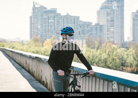 Radfahrer in Smog getönt Stadt in N95 Maske. Luftverschmutzung. Industriestadt. Mann in Maske aus Staub. Typ in Atemschutzmaske mit Filter pm 2.5. Thema Covid Stockfoto