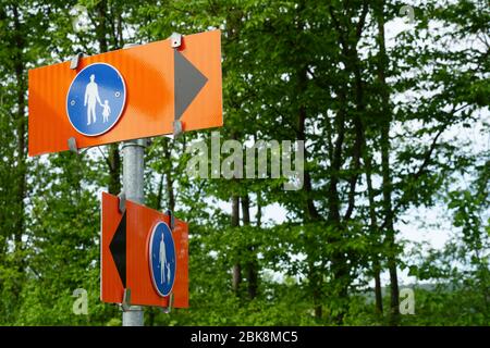 Orangefarbene Wegweiser für Fußgänger, die in zwei Richtungen weisen. Stockfoto