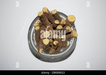 Ayurvedische Kraut Lakritz Wurzel Stick. Lakritzwurzeln, Mulethi oder Glycyrrhiza glabra in durchsichtiger Schale auf weißem Hintergrund isoliert.vorteilhaft für Ulk Stockfoto