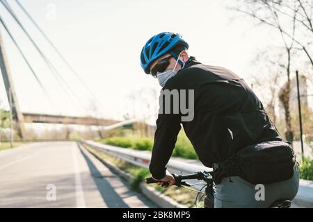 Radfahrer in Smog getönt Stadt in N95 Maske. Luftverschmutzung. Industriestadt. Mann in Maske aus Staub. Typ in Atemschutzmaske mit Filter pm 2.5. Thema Covid Stockfoto