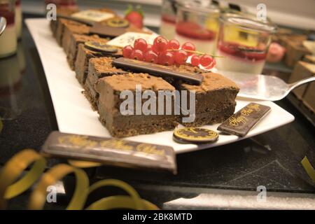 Nahaufnahme des Dessertbuffets am Neujahr. Schokoladenkuchen mit roten Johannisbeeren und Fruchtmousse in Gläsern. Reihe von individuellen Portion Desserts. Stockfoto