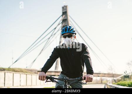 Radfahrer in Smog getönt Stadt in N95 Maske. Luftverschmutzung. Industriestadt. Mann in Maske aus Staub. Typ in Atemschutzmaske mit Filter pm 2.5. Thema Covid Stockfoto