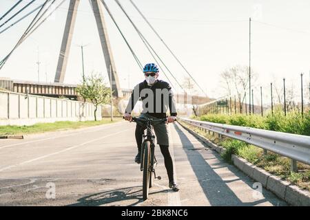 Radfahrer in Smog getönt Stadt in N95 Maske. Luftverschmutzung. Industriestadt. Mann in Maske aus Staub. Typ in Atemschutzmaske mit Filter pm 2.5. Thema Covid Stockfoto