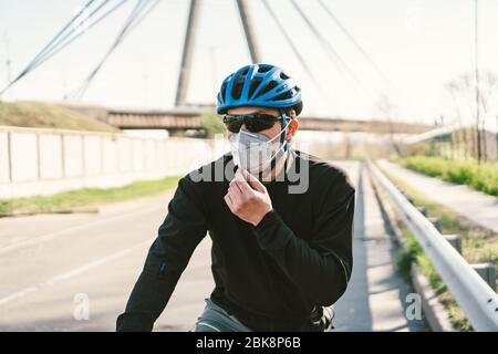 Radfahrer in Smog getönt Stadt in N95 Maske. Luftverschmutzung. Industriestadt. Mann in Maske aus Staub. Typ in Atemschutzmaske mit Filter pm 2.5. Thema Covid Stockfoto