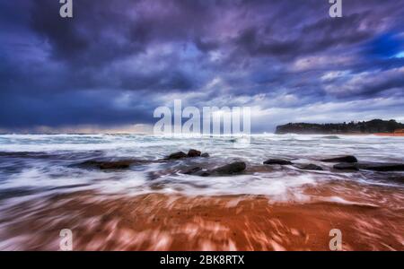 Sandstrand mit Sandsteinfelsen am Newport Beach von Sydney Nordstrände bei stürmischem Sonnenaufgangswetter. Stockfoto