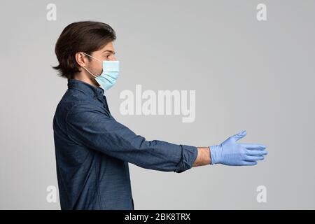 Millennial Man In Medical Maske Und Handschuhe Geben Hand Für Handshake Stockfoto