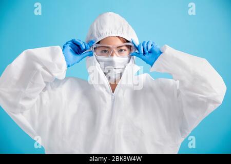 Krankenschwester mit medizinischer Maske mit Schutzbrille und weißem Schutzanzug. Stockfoto