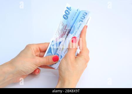 Türkische Banknotenansicht in weiblicher Hand auf weißem Hintergrund. Stockfoto