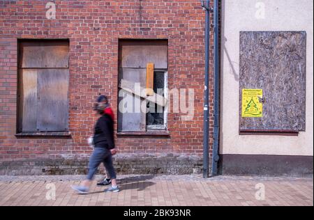 28. April 2020, Mecklenburg-Vorpommern, Bützow: Passanten gehen an den beiden leeren Wohn- und Geschäftsgebäuden in der Langen Straße vorbei. Auch fünf Jahre nach dem Tornado sind die Gebäude noch nicht renoviert worden. Fünf Jahre nach dem verheerenden Tornado wurden die meisten Gebäude in der kleinen Stadt restauriert. Der Tornado, der am Abend des 05.05.2015 durch Bützow fegte, hatte Schäden in Höhe von rund 40 Millionen Euro verursacht. Foto: Jens Büttner/dpa-Zentralbild/dpa Stockfoto