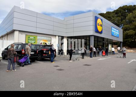 Vendrell, Spanien. Mai 2020. Eine Gruppe von Menschen mit Gesichtsmasken und Warenkörben warten in einer Warteschlange am Eingang des Lidl-Supermarktes.Supermärkte sind während dieser Gesundheitskrise unerlässlich und müssen das Sicherheitsprotokoll covid 19 einhalten, wie z. B. die Verringerung der Kapazität im Inneren, die Einhaltung eines sicheren Abstands und die Einhaltung der Bestellung, Ein Kunde verlässt, ein anderer tritt ein, um mögliche Kontakte bei einer Coronavirus-Pandemie zu vermeiden. Quelle: SOPA Images Limited/Alamy Live News Stockfoto