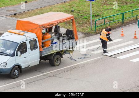 Anbringen von Straßenmarkierungen auf Asphalt mit einer speziellen Maschine. Redaktionell Stockfoto