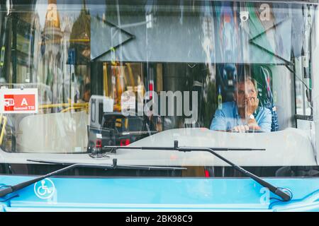 Moskau, Russland - 7. JULI 2017: Ein Stadtbusfahrer sitzt und nutzt das Telefon an einer Haltestelle wartet auf Passagiere Stockfoto