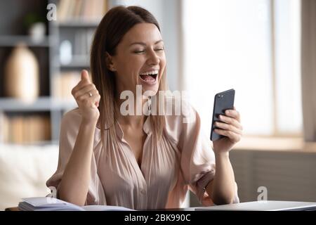 Aufgeregt Frau Blick auf Telefon-Bildschirm, feiern Online-Sieg Stockfoto