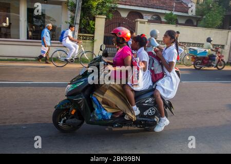 Sri Lanka Mutter und Schule gehen Kinder auf einem Roller in Negombo, Srilanka fahren. Stockfoto