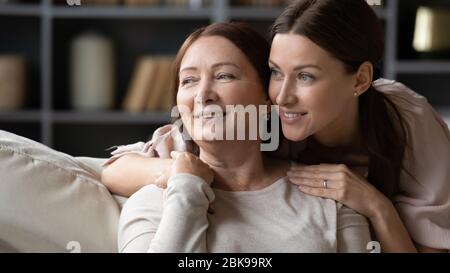 Lächelnd reife Mutter und Erwachsene Tochter umarmen, in der Ferne suchen Stockfoto