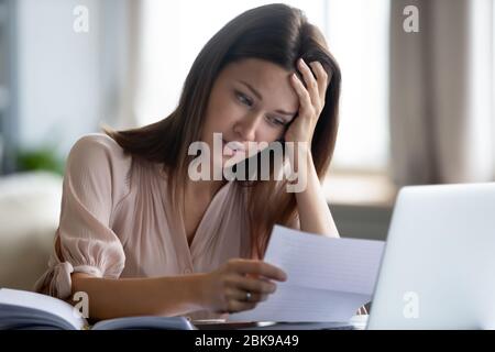 Unglückliche Frau, die Papier hält, schlechte Nachrichten im Brief liest Stockfoto