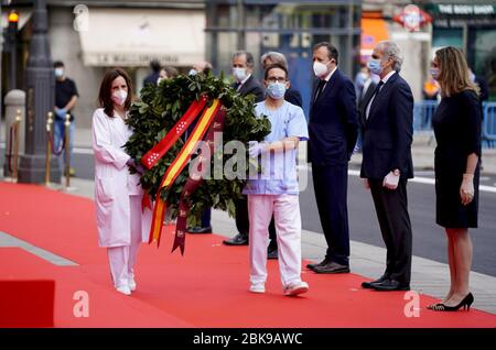 (200503) -- MADRID, 3. Mai 2020 (Xinhua) -- zwei Gesundheitshelfer tragen einen Blumenkranz während eines Schweigens, der am 2. Mai 2020 für die Opfer der COVID-19 auf dem Platz Puerta del Sol in Madrid, Spanien, beobachtet wurde. (Regierung der Region Madrid/Handout über Xinhua) Stockfoto