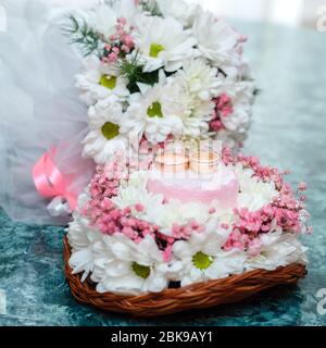 Zwei goldene Eheringe auf schönem weißen und rosa Bouquet in rustikalem Korbflecht. Nahaufnahme. Stockfoto