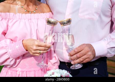 Braut und Bräutigam mit Sektgläsern und Brautstrauß Stockfoto
