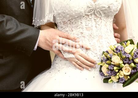 Hände des Bräutigams und der Braut Nahaufnahme und Brautstrauß Stockfoto