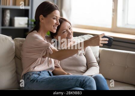 Lächelnde Mutter und Tochter mittleren Alters, die zusammen Selfie machen Stockfoto