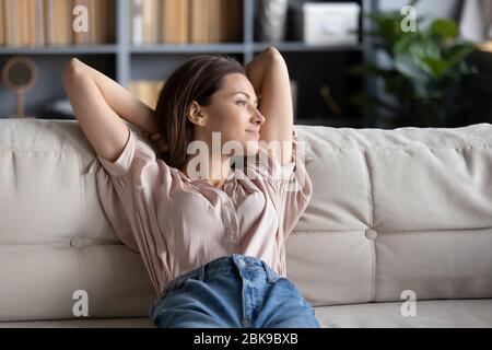 Friedliche junge Frau, die sich zu Hause auf der Couch entspannt Stockfoto